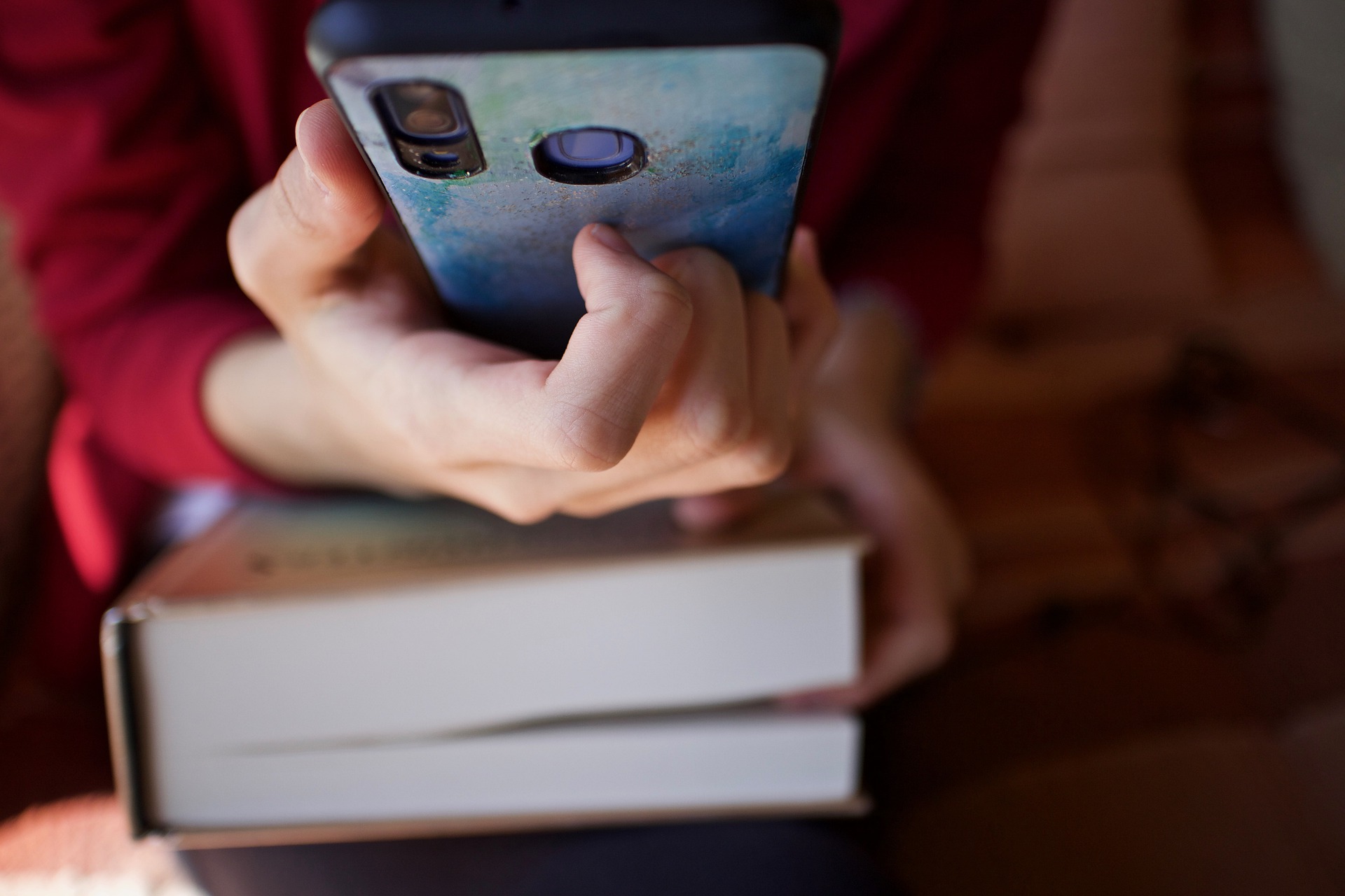 Woman holding phone above book